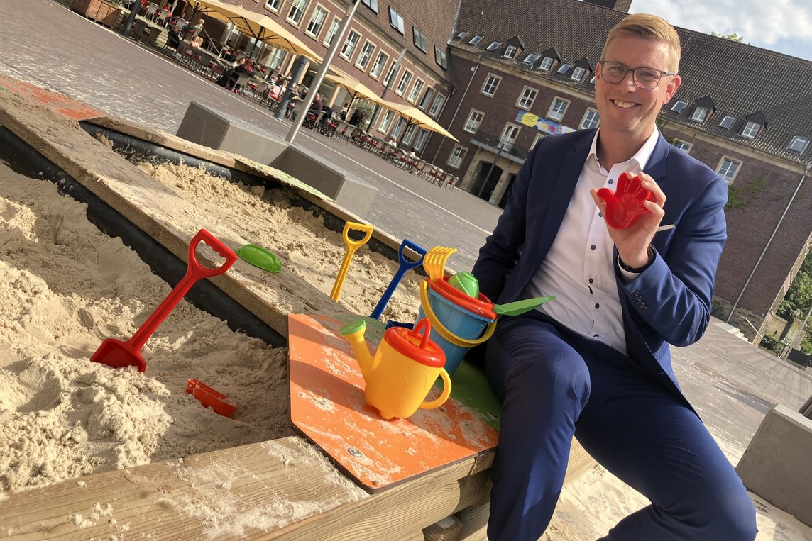 Dieses Foto zeigt Bürgermeister Carsten Hövekamp vor dem Sandkasten auf dem Marktplatz