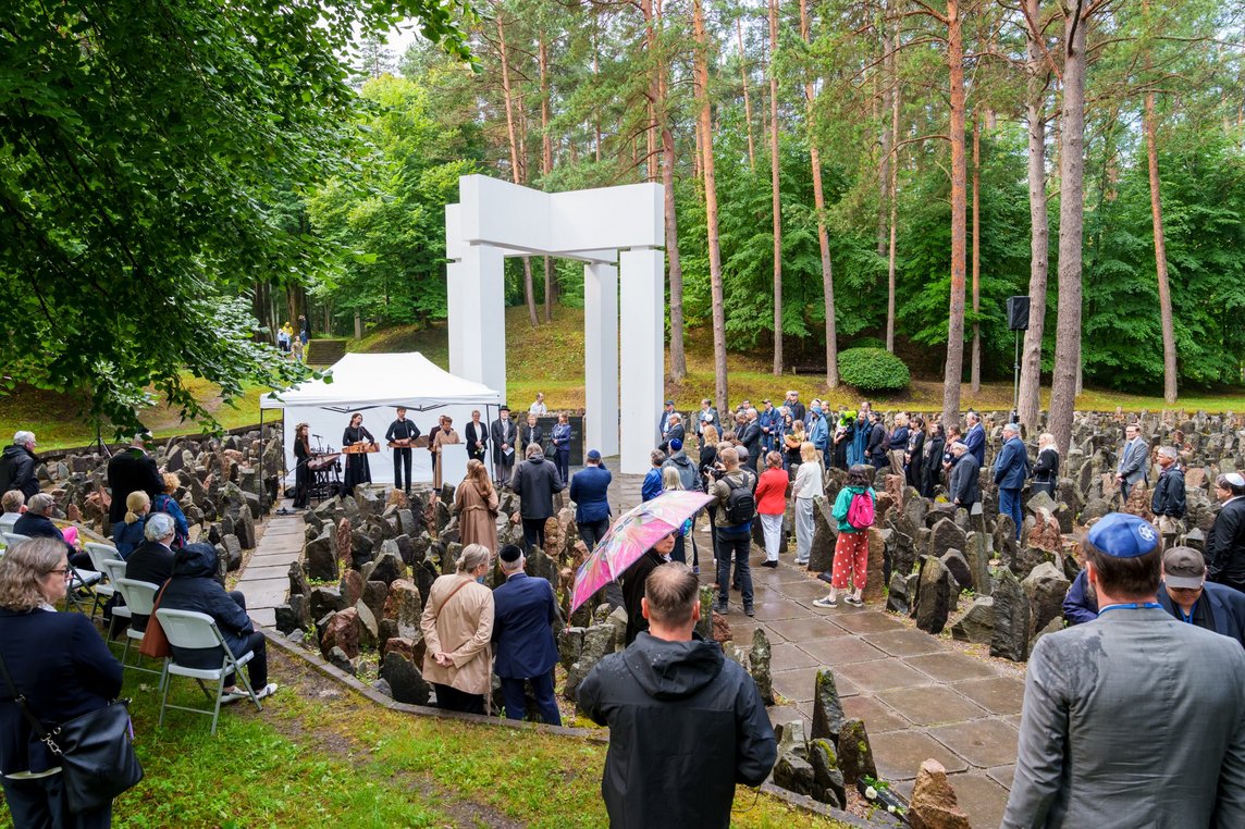 Das Foto zeigt viele Menschen vor der Gedenkstätte im Wald.
