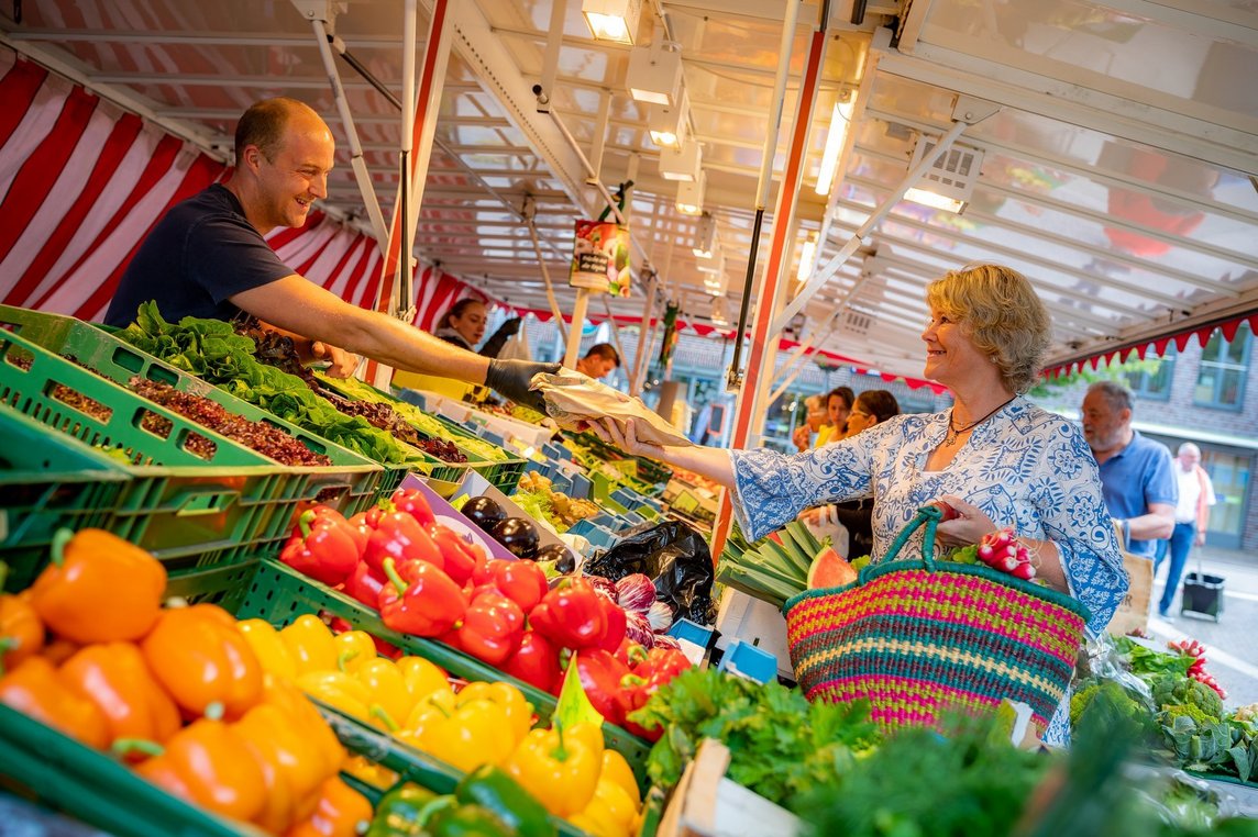 Das Bild zeigt eine Frau beim Einkauf am Marktstand.