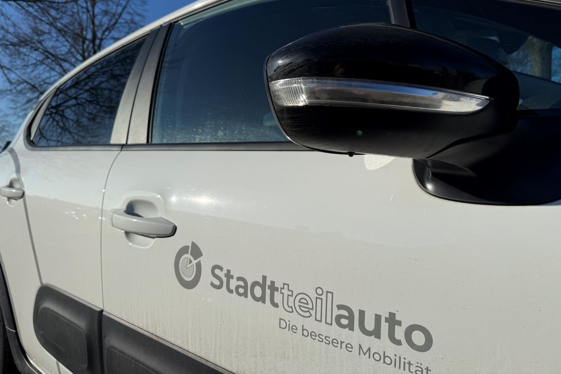 Das Foto zeigt ein weißes Auto mit der Aufschrift "Stadtteilauto".