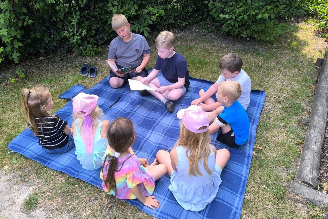 Dieses Foto zeigt, wie Grundschulkinder den Kitakinder vorlesen. 